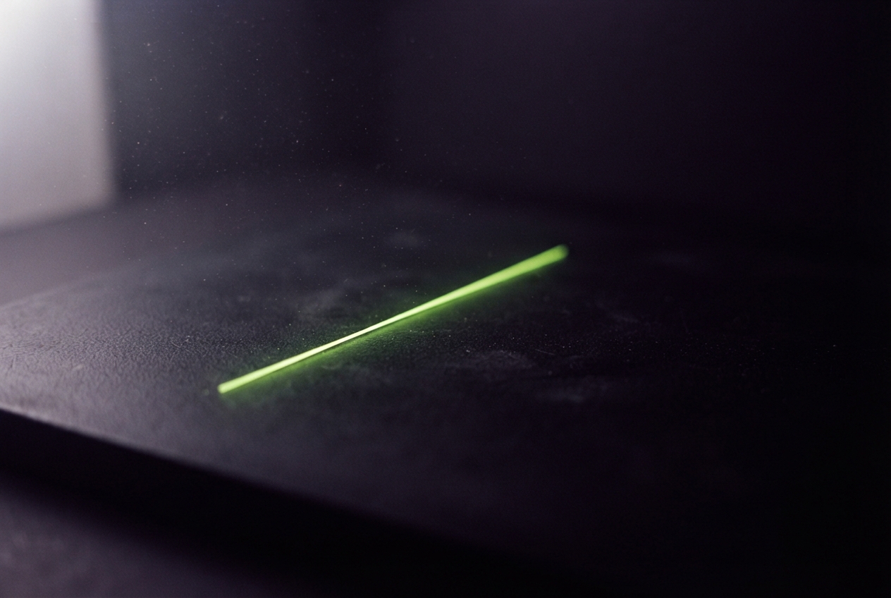 A thin glowing green line lies diagonally across a dark, textured surface.